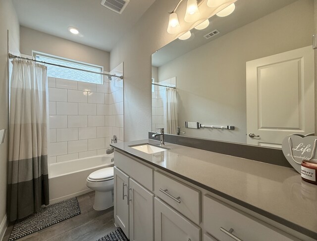 bathroom featuring toilet, vanity, wood finished floors, and visible vents