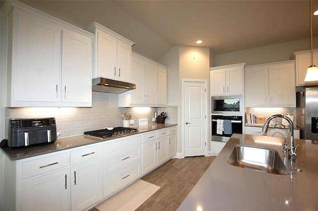 kitchen featuring under cabinet range hood, white cabinets, appliances with stainless steel finishes, and a sink