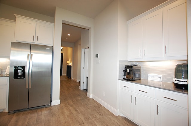 kitchen with white cabinetry, decorative backsplash, baseboards, light wood-type flooring, and stainless steel refrigerator with ice dispenser