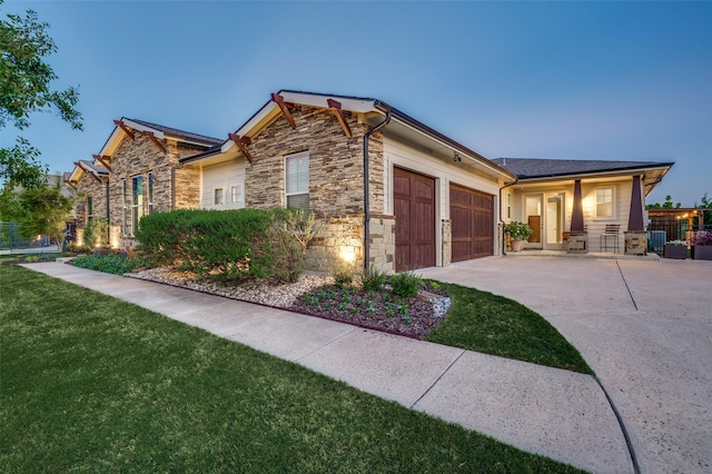 exterior space featuring concrete driveway, stone siding, fence, a yard, and a garage
