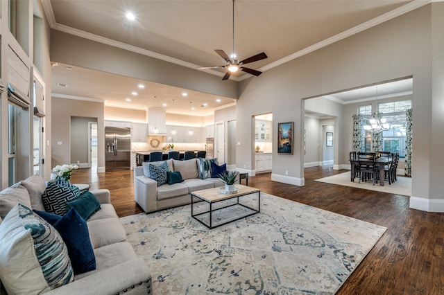 living area featuring baseboards, recessed lighting, ceiling fan with notable chandelier, wood finished floors, and crown molding