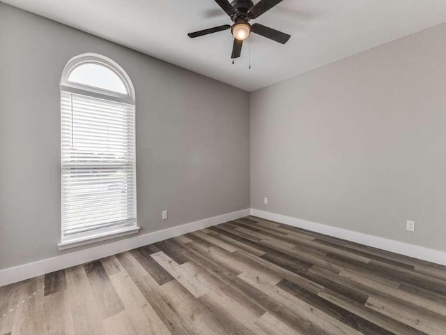 empty room featuring wood finished floors, baseboards, and ceiling fan