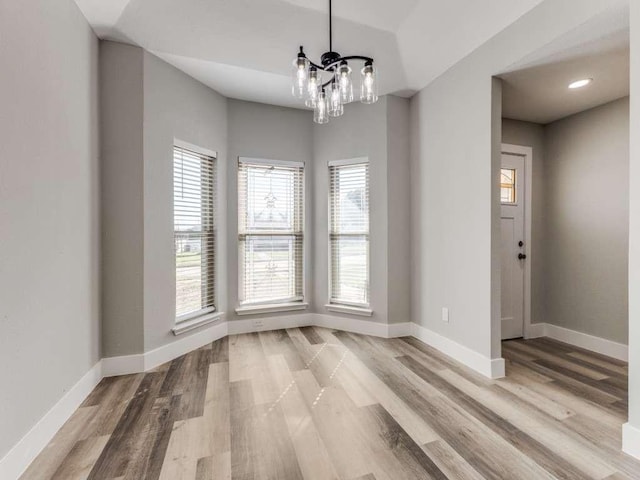 unfurnished dining area with recessed lighting, light wood-type flooring, baseboards, and a notable chandelier