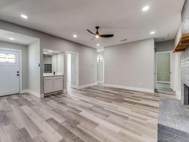 unfurnished living room with baseboards, recessed lighting, light wood-style floors, a brick fireplace, and ceiling fan