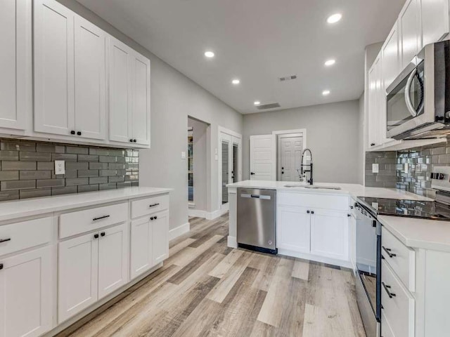 kitchen featuring decorative backsplash, appliances with stainless steel finishes, a sink, and white cabinetry
