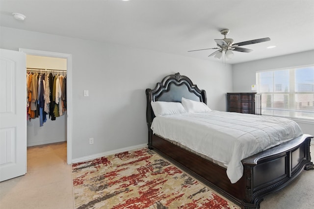 bedroom with a ceiling fan, a closet, baseboards, a spacious closet, and light colored carpet