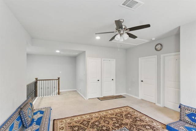 unfurnished room featuring light carpet, attic access, a ceiling fan, and visible vents