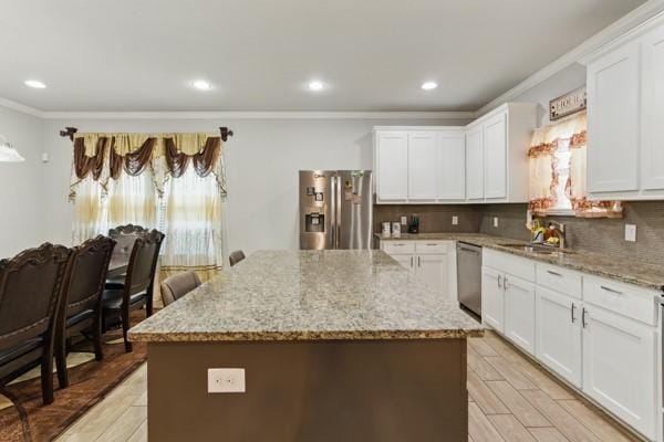 kitchen with a sink, stainless steel appliances, ornamental molding, recessed lighting, and a center island
