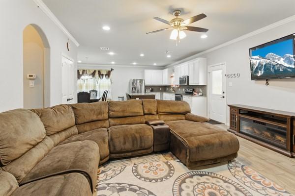 living room with ceiling fan, crown molding, arched walkways, and recessed lighting