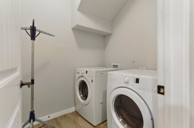 washroom featuring baseboards, separate washer and dryer, light wood finished floors, and laundry area