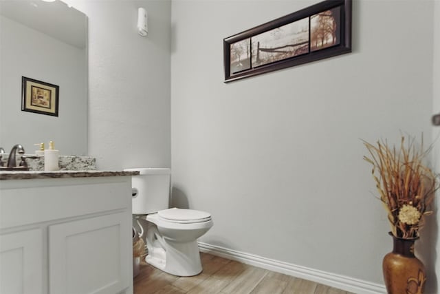 bathroom with vanity, toilet, baseboards, and wood finished floors
