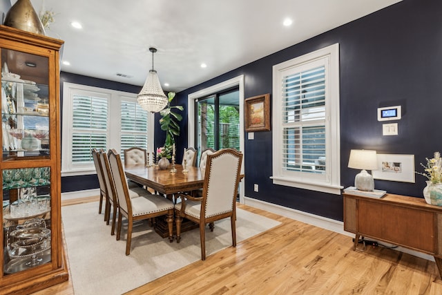 dining area with a chandelier, light wood-style floors, visible vents, and baseboards