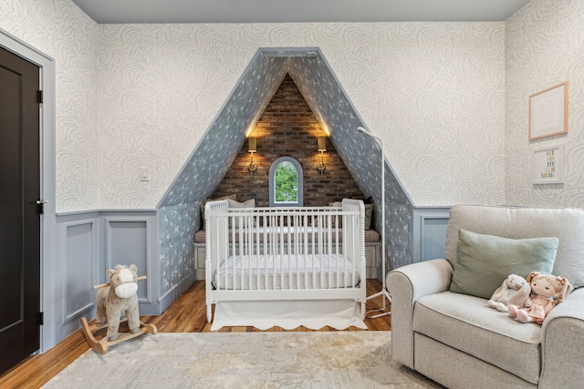 bedroom with a nursery area and wood finished floors