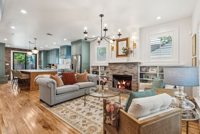 living room with light wood-type flooring, visible vents, an inviting chandelier, recessed lighting, and a fireplace