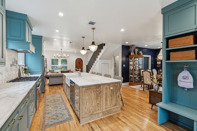 kitchen featuring stainless steel appliances, visible vents, light wood-style floors, light stone countertops, and a notable chandelier
