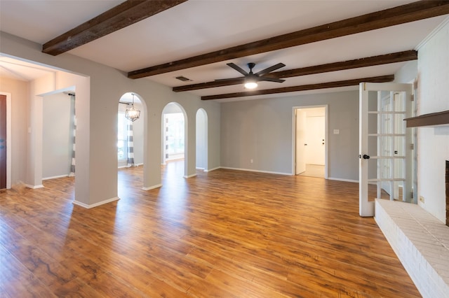 1904 Park Hill Dr, Arlington, TX 76012 - unfurnished living room with beamed ceiling, arched walkways, a ceiling fan, baseboards, and light wood-style floors