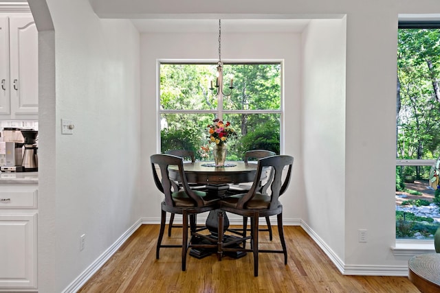 dining area featuring arched walkways, baseboards, and light wood-type flooring