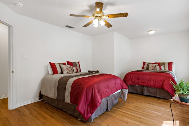 bedroom featuring visible vents, baseboards, a ceiling fan, and wood finished floors