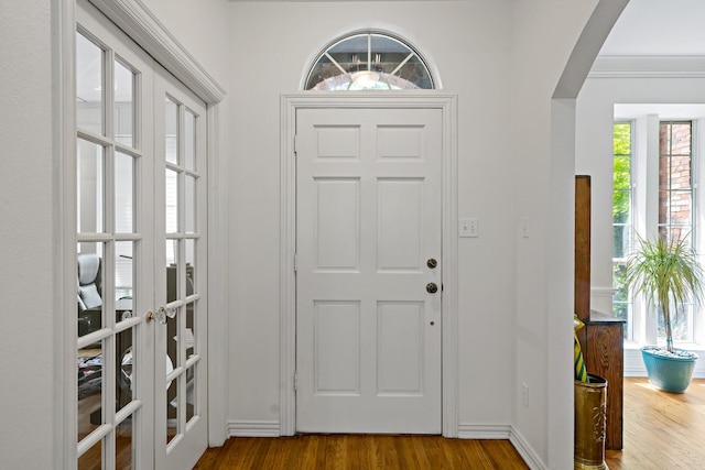entrance foyer featuring french doors, baseboards, arched walkways, and dark wood finished floors