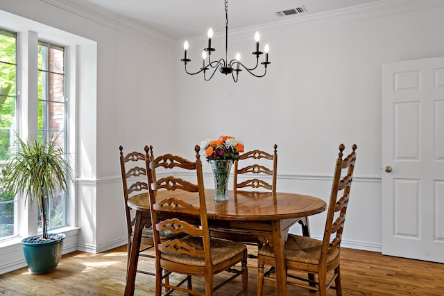dining area with plenty of natural light, an inviting chandelier, visible vents, ornamental molding, and light wood-style floors