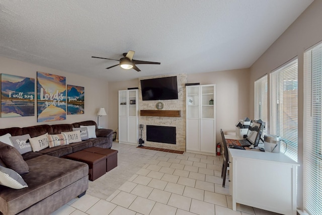 living room with a textured ceiling, light colored carpet, ceiling fan, a fireplace, and light tile patterned floors