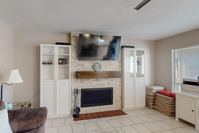 tiled living room featuring a stone fireplace and a textured ceiling