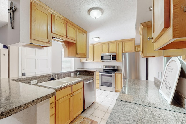 kitchen with a sink, a textured ceiling, light brown cabinetry, light tile patterned floors, and appliances with stainless steel finishes