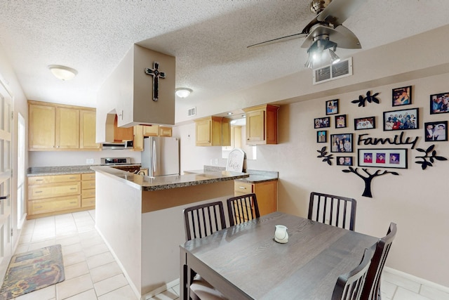 dining room with a ceiling fan, visible vents, a textured ceiling, and light tile patterned floors