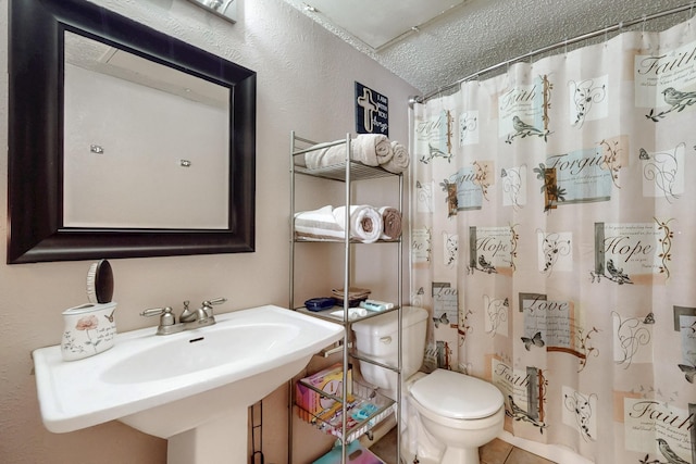 bathroom with a textured ceiling, a sink, a shower with curtain, toilet, and tile patterned flooring