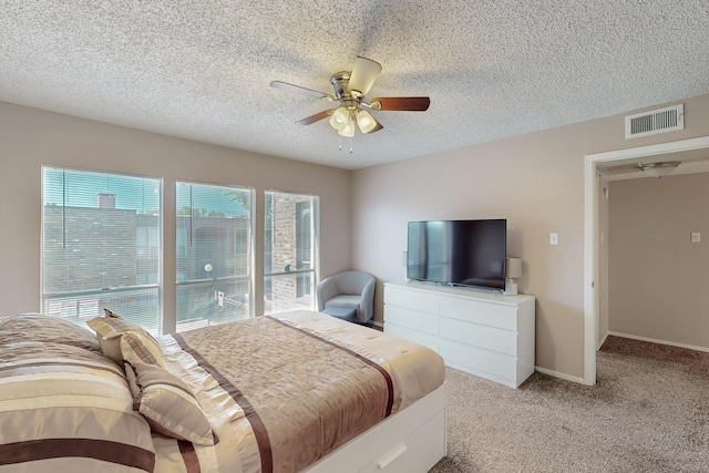 bedroom featuring visible vents, a ceiling fan, baseboards, a textured ceiling, and light colored carpet