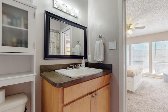 full bath with vanity, a textured ceiling, toilet, a ceiling fan, and ensuite bath