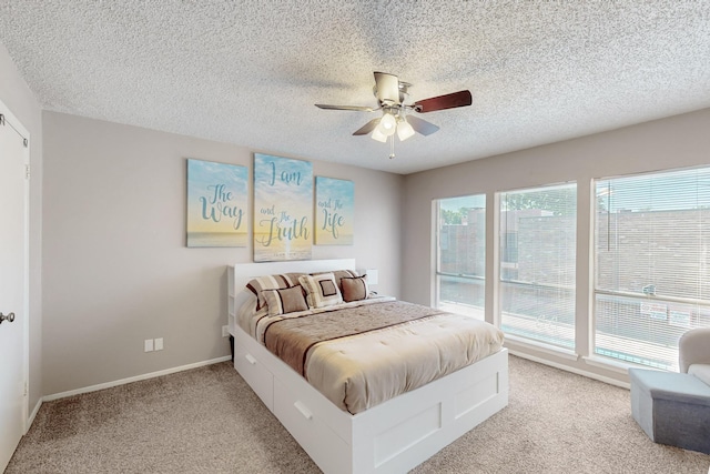 bedroom with light carpet, a ceiling fan, baseboards, and a textured ceiling