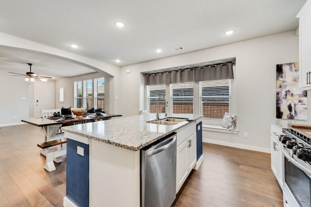 1008 Shire Dr, Aubrey, TX 76227 - kitchen featuring wood finished floors, a ceiling fan, a sink, arched walkways, and appliances with stainless steel finishes
