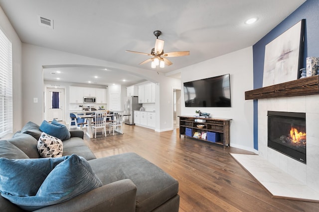 1008 Shire Dr, Aubrey, TX 76227 - living area featuring a ceiling fan, a fireplace, visible vents, arched walkways, and light wood-style floors