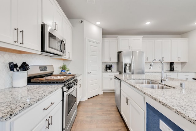 1008 Shire Dr, Aubrey, TX 76227 - kitchen featuring a sink, light wood-type flooring, white cabinetry, appliances with stainless steel finishes, and decorative backsplash