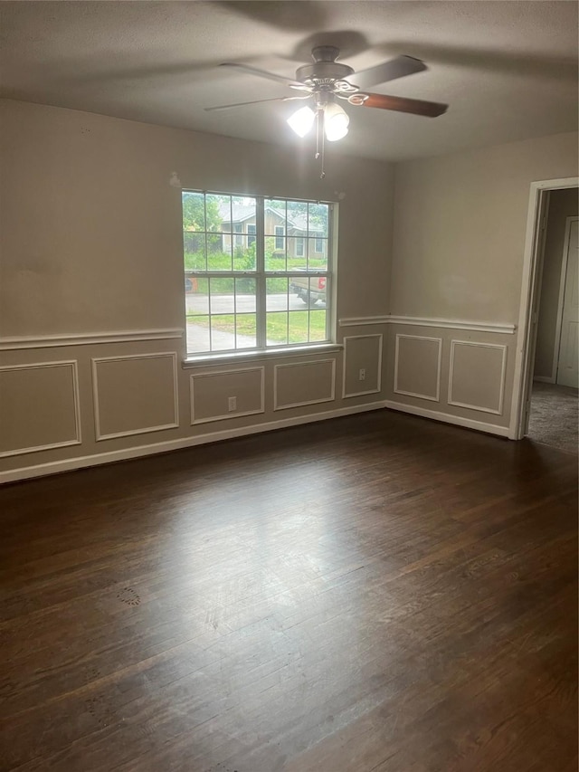 empty room with wainscoting, a ceiling fan, and a decorative wall