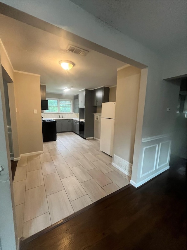 kitchen featuring light countertops, a sink, visible vents, and freestanding refrigerator