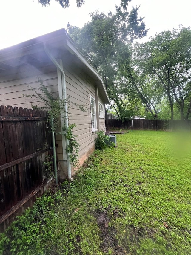 view of side of home with a fenced backyard and a lawn