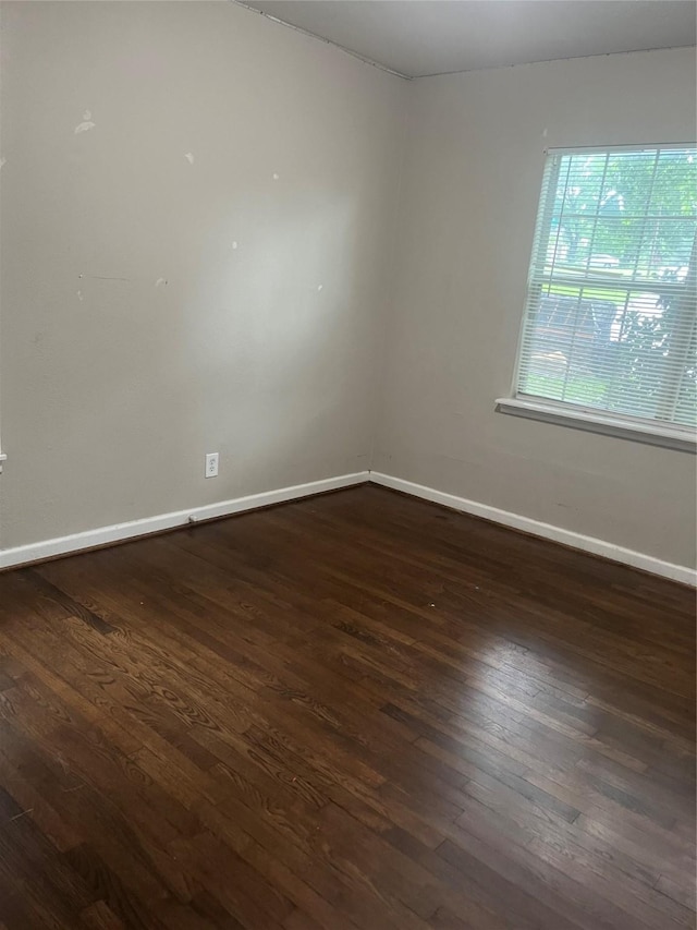 empty room featuring baseboards and dark wood-type flooring