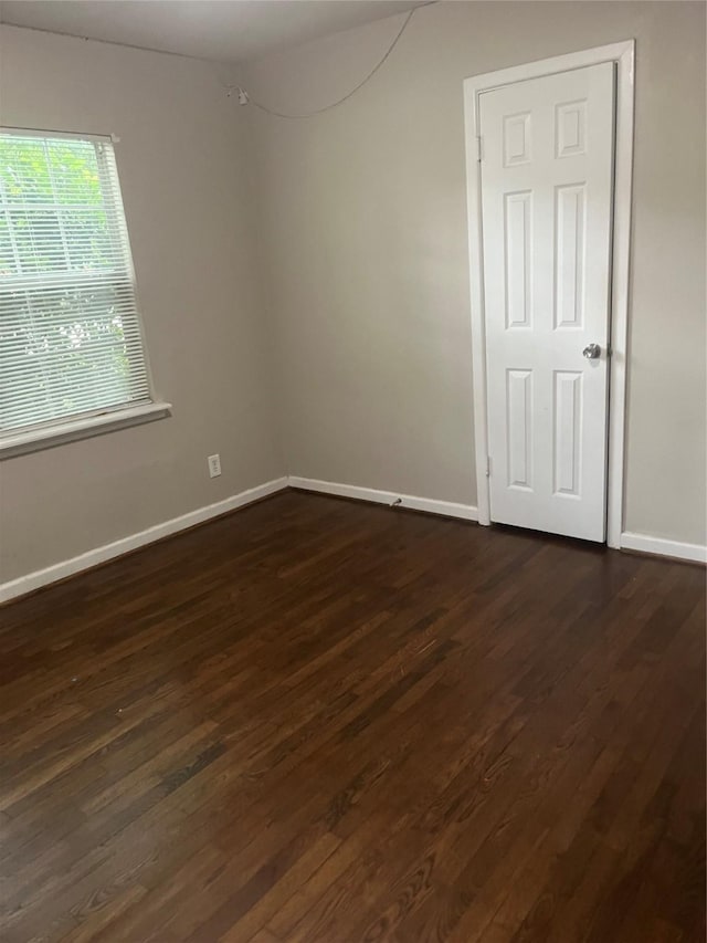 unfurnished room with baseboards and dark wood-type flooring