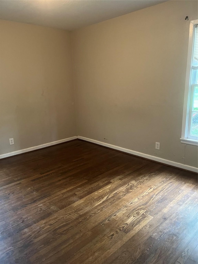 empty room featuring baseboards and dark wood-style floors