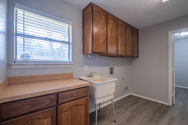 laundry room with a textured ceiling, baseboards, hookup for a washing machine, cabinet space, and dark wood-type flooring