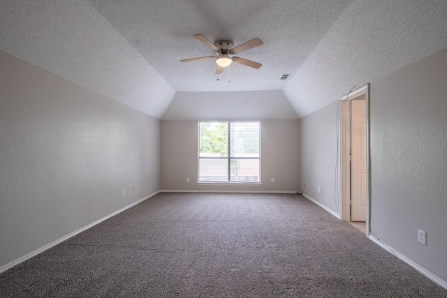 interior space featuring a textured ceiling, ceiling fan, baseboards, lofted ceiling, and visible vents