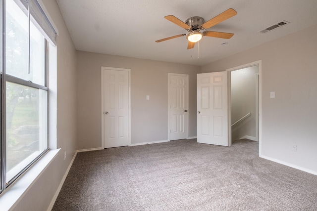 unfurnished bedroom with carpet floors, multiple windows, and visible vents