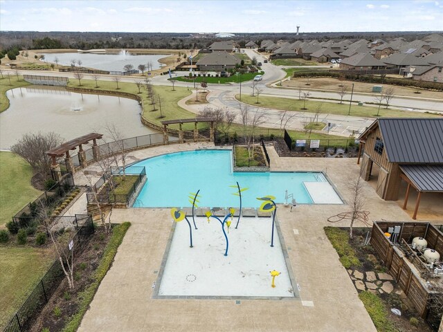 pool with fence, a water view, and a residential view