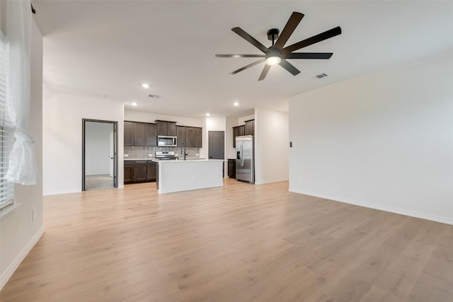unfurnished living room with ceiling fan, light wood-type flooring, visible vents, and baseboards