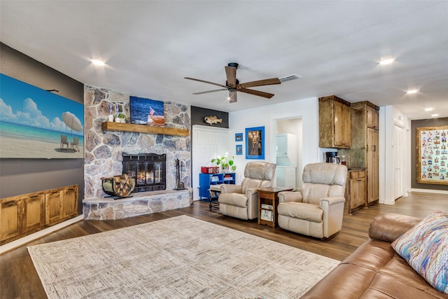 living area featuring visible vents, wood finished floors, a ceiling fan, and a fireplace