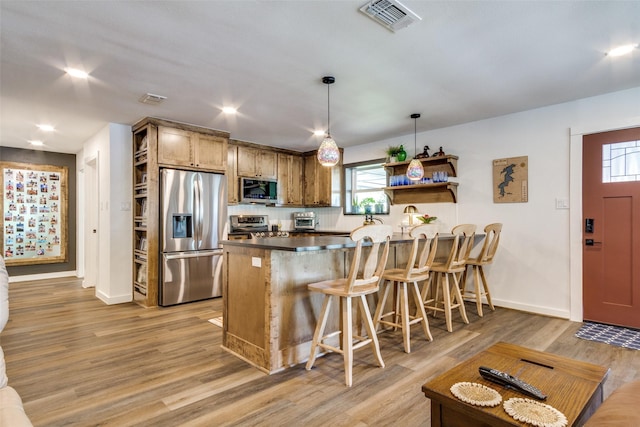 kitchen with a peninsula, light wood-type flooring, visible vents, baseboards, and appliances with stainless steel finishes