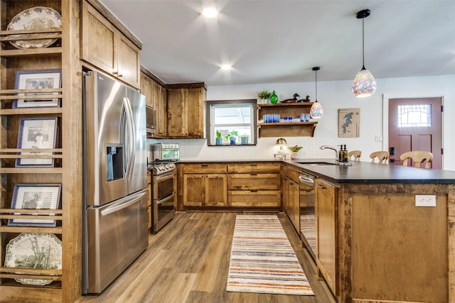 kitchen featuring light wood finished floors, a peninsula, a sink, open shelves, and appliances with stainless steel finishes