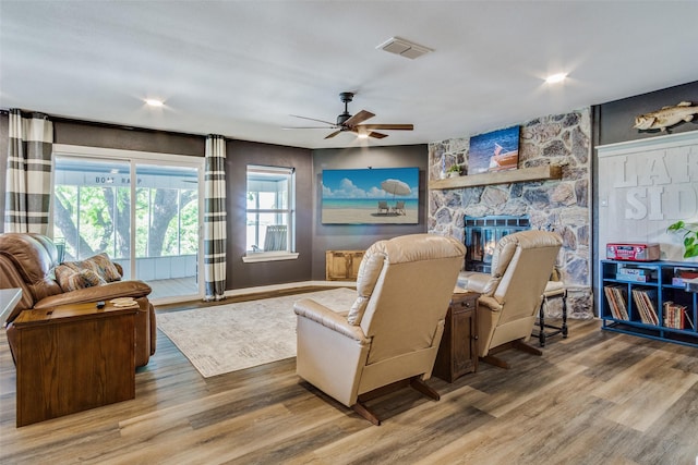 living room with a fireplace, ceiling fan, visible vents, and wood finished floors